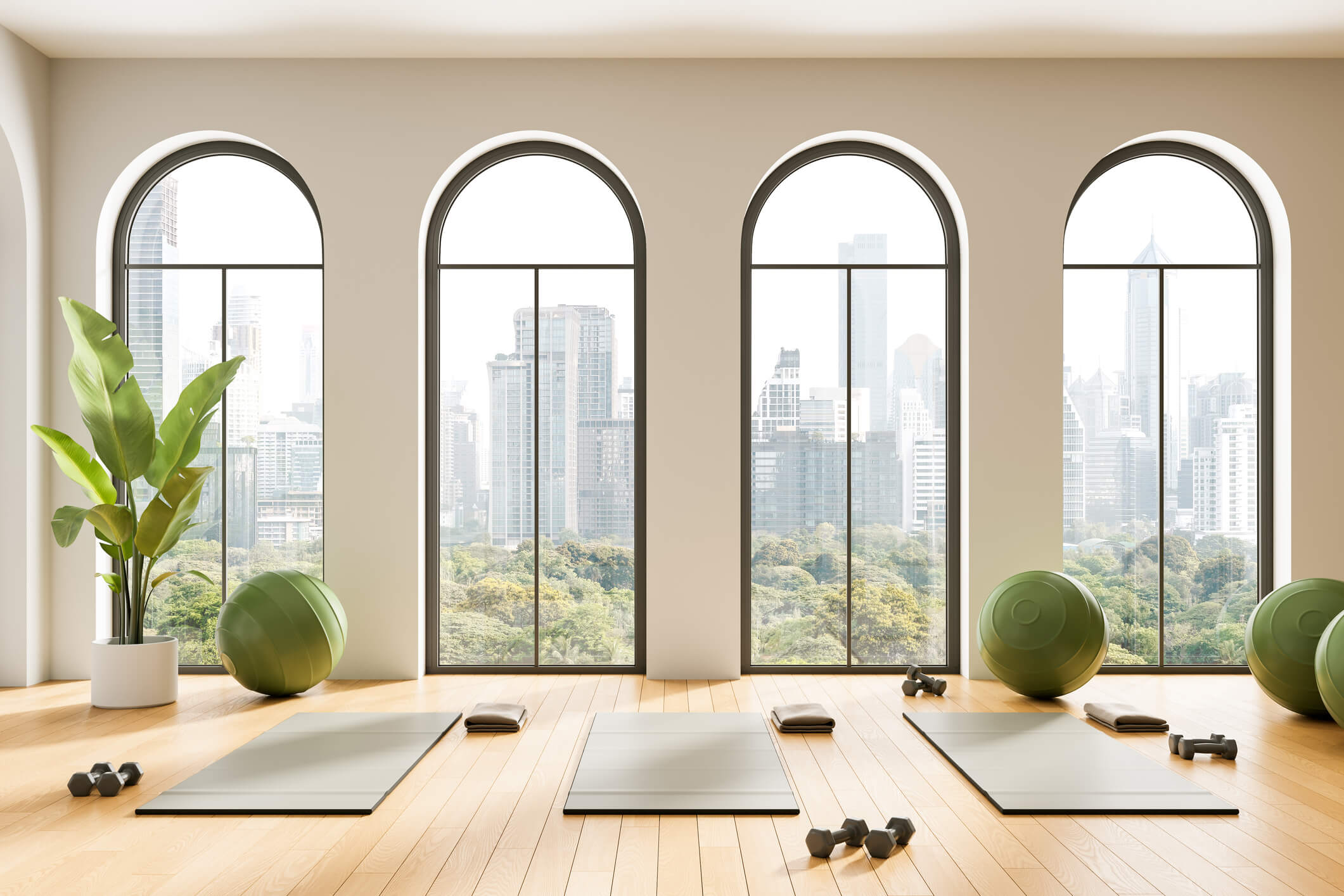 Minimalist yoga studio with large arched windows overlooking a city skyline.